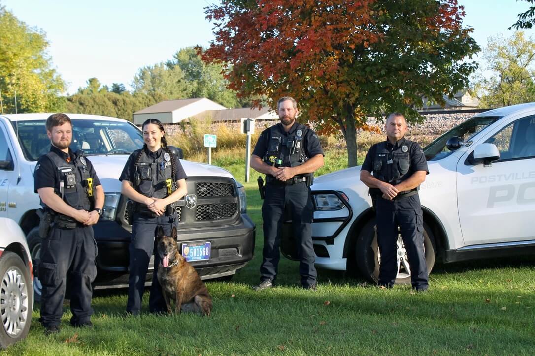 Postville Police officers poses outside with their vehicles.